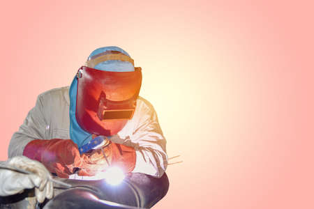 worker welding arc welder wear equipment protection mask on pink color background for coppy spaceの写真素材