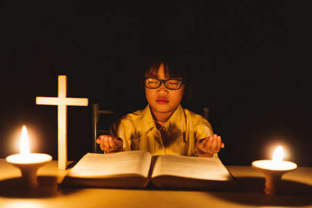 Cute little girl with glasses praying to the GODの写真素材
