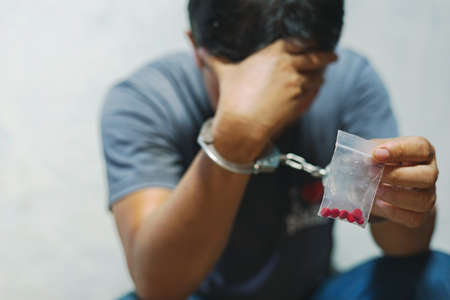 Drug dealer under arrest confined with handcuffs and hands, sale of drugs is punishable by law.の写真素材