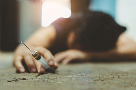 Male of a drug addict and a syringe with narcotic syringe lying on the floor. Anti drug concept.