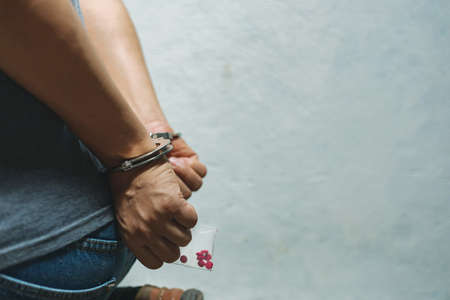 Drug dealer under arrest confined with handcuffs and hands, sale of drugs is punishable by law.の素材 [FY310153556617]