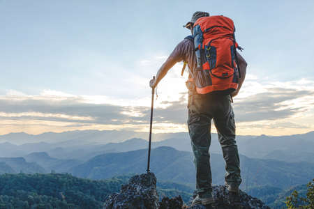 Hiker with backpack standing on top mountain sunset background. Hiker man hiking living healthy active lifestyle.の写真素材