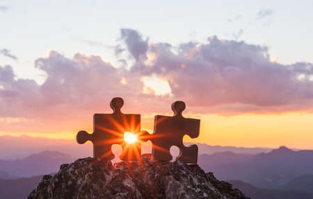 connect couple puzzle piece with sunset background. empty copy space. Jigsaw wooden puzzle against sun. one part of whole. symbol of association and connection. business strategy.の写真素材