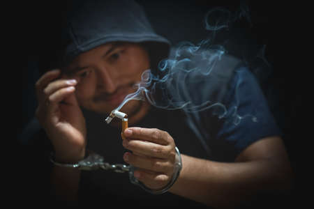 Young man of prisoner in handcuffs breaking cigarette. Quitting smoking habit.の写真素材