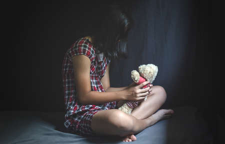 Sad girl sitting in dark bedroom.stop violence against Women,の写真素材