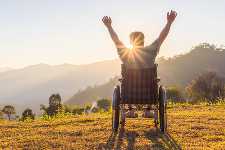 Disabled handicapped man is sitting on wheelchair at sunset.の写真素材