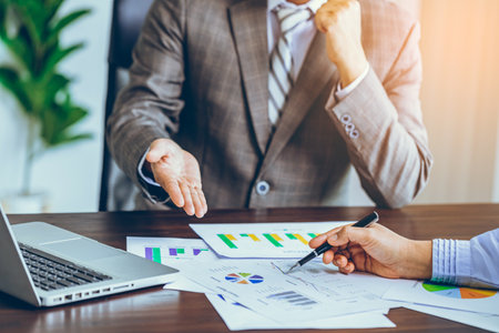 Two successful business partners working on business documents on office table with laptop working in the backgroundの写真素材