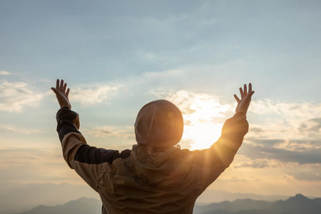 man hand raising on top of mountain and sunset sky abstract background.の写真素材