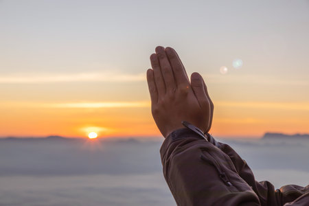 Close up praying hands praying for thank god golden sunrise mist mountain background. Concept of...