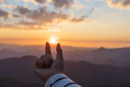 Female hand signs gesture to be little heart from tip of thumb and index finger in golden color sunset background. valentines day conceptの写真素材