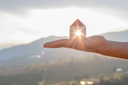 House in hand nature sunset background. protection or property concept.の写真素材