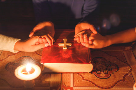 Group of people holding hands praying worship believe with lighting candle at night...