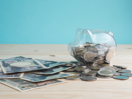 transparent see through piggy bank filled with coins on wood background.Saving investment colorful concept.の写真素材