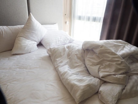 Top view of the crease of an unmade bed sheet in the bedroom after night sleep and waking up in the morning.White blanket. Wrinkle messy blanket in bedroom after waking up in the morning. Bed details. blanket, an unmade bed in hotel bedroom with white blaの写真素材