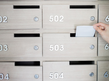 Close-up of person's hand . hand removing a letter from mailbox in the entrance hall of an apartment...