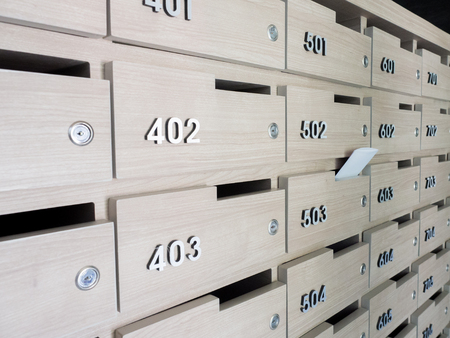 Close-up of person's hand . hand removing a letter from mailbox in the entrance hall of an apartment buildingの写真素材