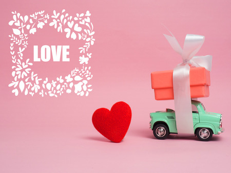 Vintage car carry a  gift box on color background and top wood table for Christmas and The New Year and Valentine's day .Decoration love heart .の写真素材