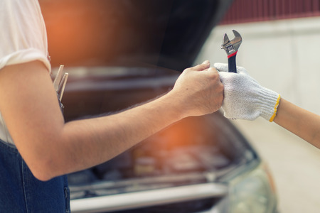 Mechanic hand checking and fixing a broken car in  garage.hand of mechanic with thumbs up and toolの写真素材