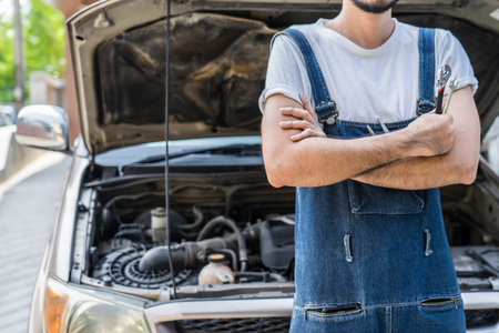 Fixing car engine in automobile repair garage. Handsome mechanics in uniform are repairing car while working in auto serviceの写真素材