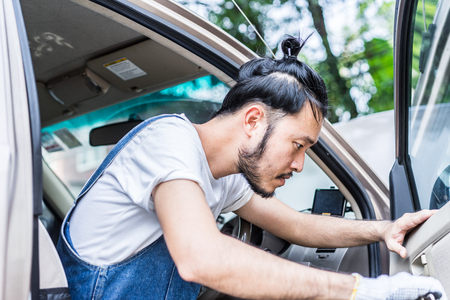 Fixing car engine in automobile repair garage. Handsome mechanics in uniform are repairing car while working in auto serviceの写真素材