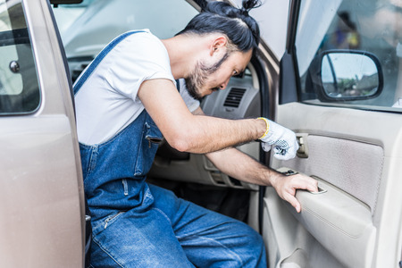 Fixing car engine in automobile repair garage. Handsome mechanics in uniform are repairing car while working in auto serviceの写真素材