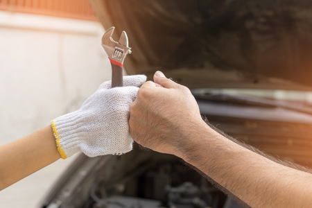 Mechanic hand checking and fixing a broken car in  garage.hand of mechanic with thumbs up and toolの写真素材