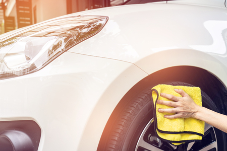 A man cleaning white car with yellow microfiber cloth.の写真素材