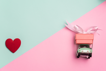 Vintage car carry a  gift box on color background and top wood table for Christmas and The New Year and Valentine's day .Decoration love heart .の写真素材