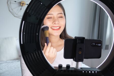 Portrait of young asian woman review giveaway gift product fan following channel, recording video make up lipstic cosmetic at home. Beauty blogger present beauty cosmeticsの写真素材