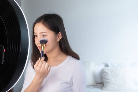 Portrait of young asian woman review giveaway gift product fan following channel, recording video make up lipstic cosmetic at home. Beauty blogger present beauty cosmeticsの写真素材
