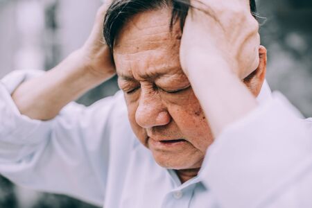 Portrait of an elderly man with headache.senior man covering his face with his hands.vintage tone