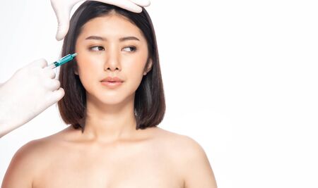 Asian young woman gets injection in her lips. Woman in beauty salon. plastic surgery clinic. Beautiful woman gets injection in her face.の写真素材