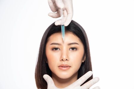 Asian young woman gets injection in her lips. Woman in beauty salon. plastic surgery clinic. Beautiful woman gets injection in her face.の写真素材