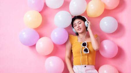 Asian Beauty girl with colorful air balloons laughing over pink background. Young woman on birthday...