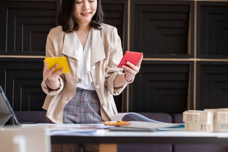 Architect or interior designer working with material sample board in showroom. Business of Real estate, home decoration .Creative people workplace.  young designer woman working with color palette at office desk.の写真素材