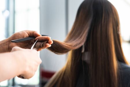 Young Asian beautiful woman having her hair cut at the hairdresser's..Scissors cut the girls hair.Barber student cutting hair using puppetの写真素材