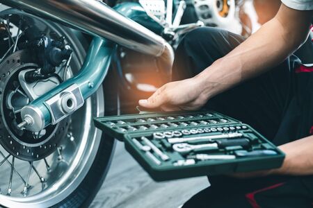 Bike repair. Young man repairing  motobike in garage.mechanic fixing motocycle engine.Serious young man repairing his motorcycle in bike repair shop.の写真素材