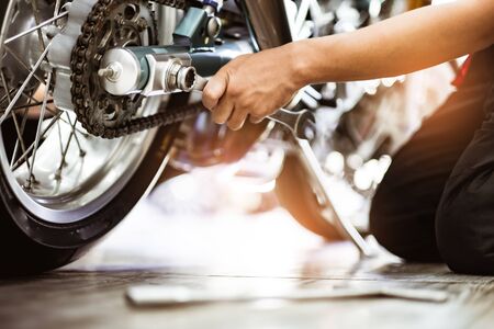 Bike repair. Young man repairing  motobike in garage.mechanic fixing motocycle engine.Serious young man repairing his motorcycle in bike repair shop.の写真素材