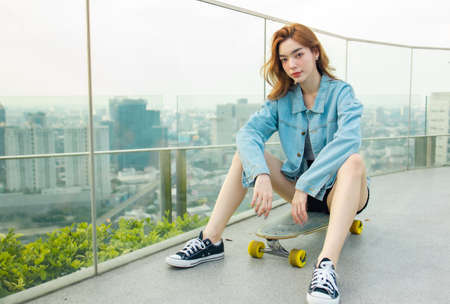 Asian young women surf skate or skates board outdoors on beautiful summer day. Happy young women...