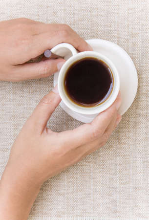 Close up two hands with white coffee cup on sack background.の写真素材