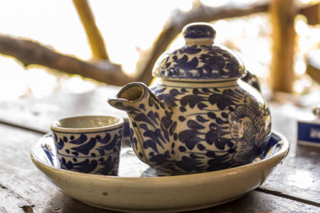An antique chinese teapot and small dish.