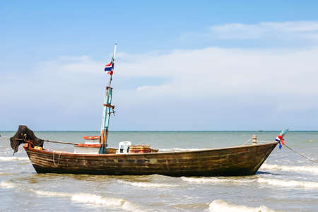 Image view of wooden boat on water with blue sky background.