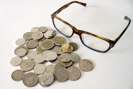 Baht Thai Coins Stacked And Eyeglasses Isolated On White Background.