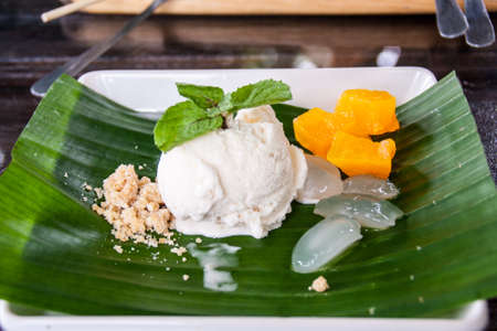 Fresh Coconut Ice Cream Is Placed On Green Banana Leaves In A White Dish.