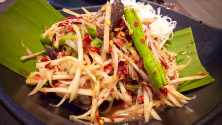 Thai Papaya Salad Or Som Tam Hot Spices On Green Banana Leaf In Black Dish.の写真素材