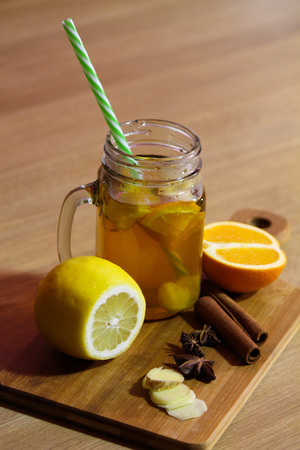 Hot tea with lemon, orange and ginger on wooden boardの写真素材