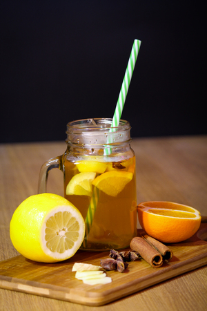 Hot tea with lemon, orange and ginger on wooden boardの写真素材
