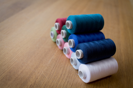 Color sewing threads on wooden tableの写真素材