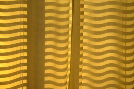 Curved and straight shadow lines on a curtainの写真素材