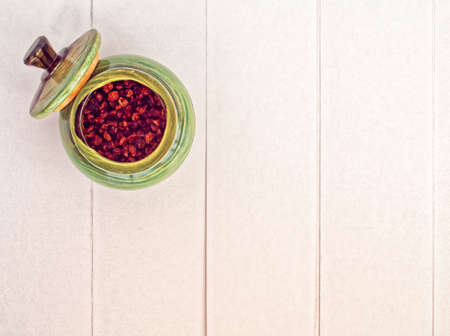 Dried raspberries in a green ceramic pot with a lid on a background of white boardsの写真素材
